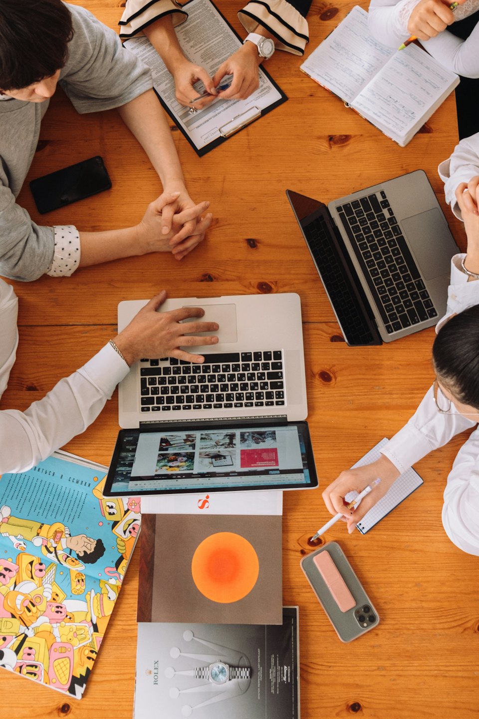 Professionals collaborating around a table with laptops and documents.